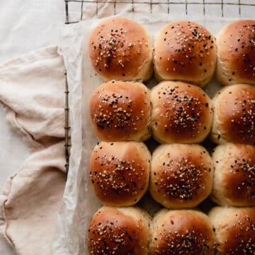 One dozen milk bread dinner rolls topped with everything but the bagel seasoning sitting on a cooling rack