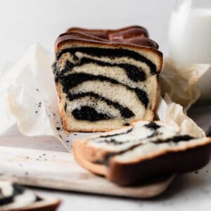 Japanese milk bread loaf with swirls of black sesame paste cut into slices on top of a cutting board